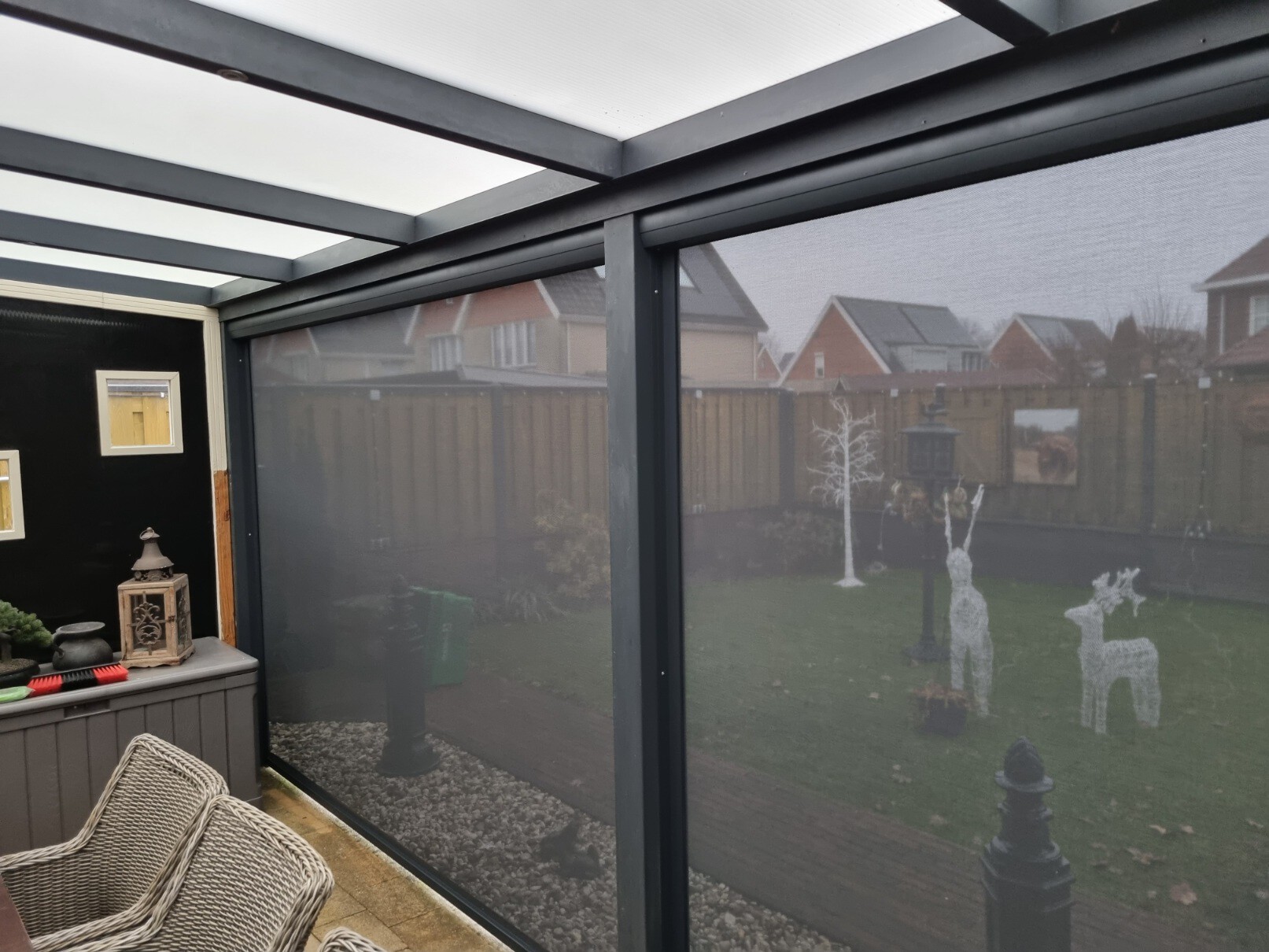 Screens voor de open zijden van een overkapping in tuin met twee kunstof sierherten op een gazon