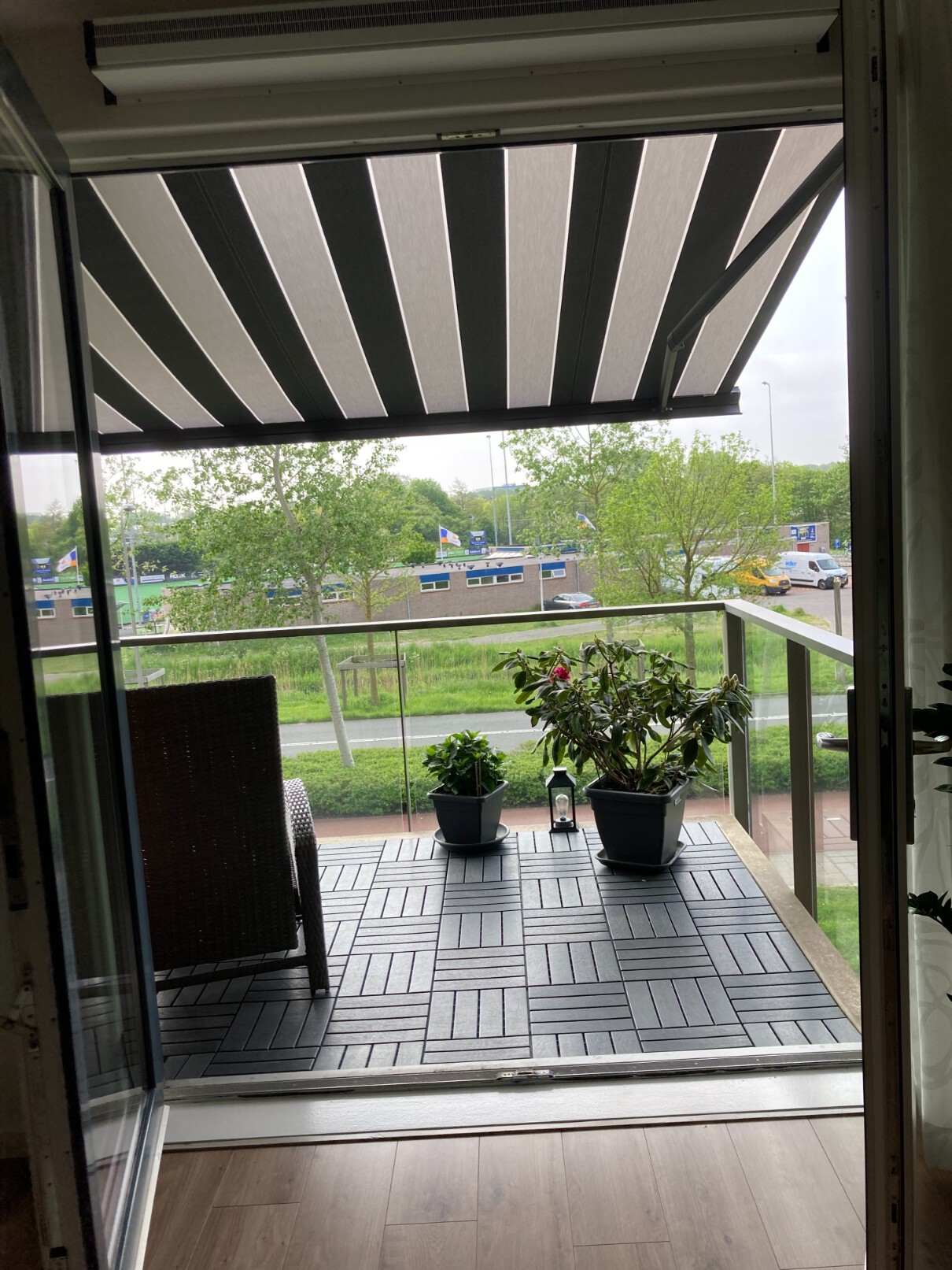 Horizontaal zonnescherm op het balkon met gestreept doek en knikarmsysteem.