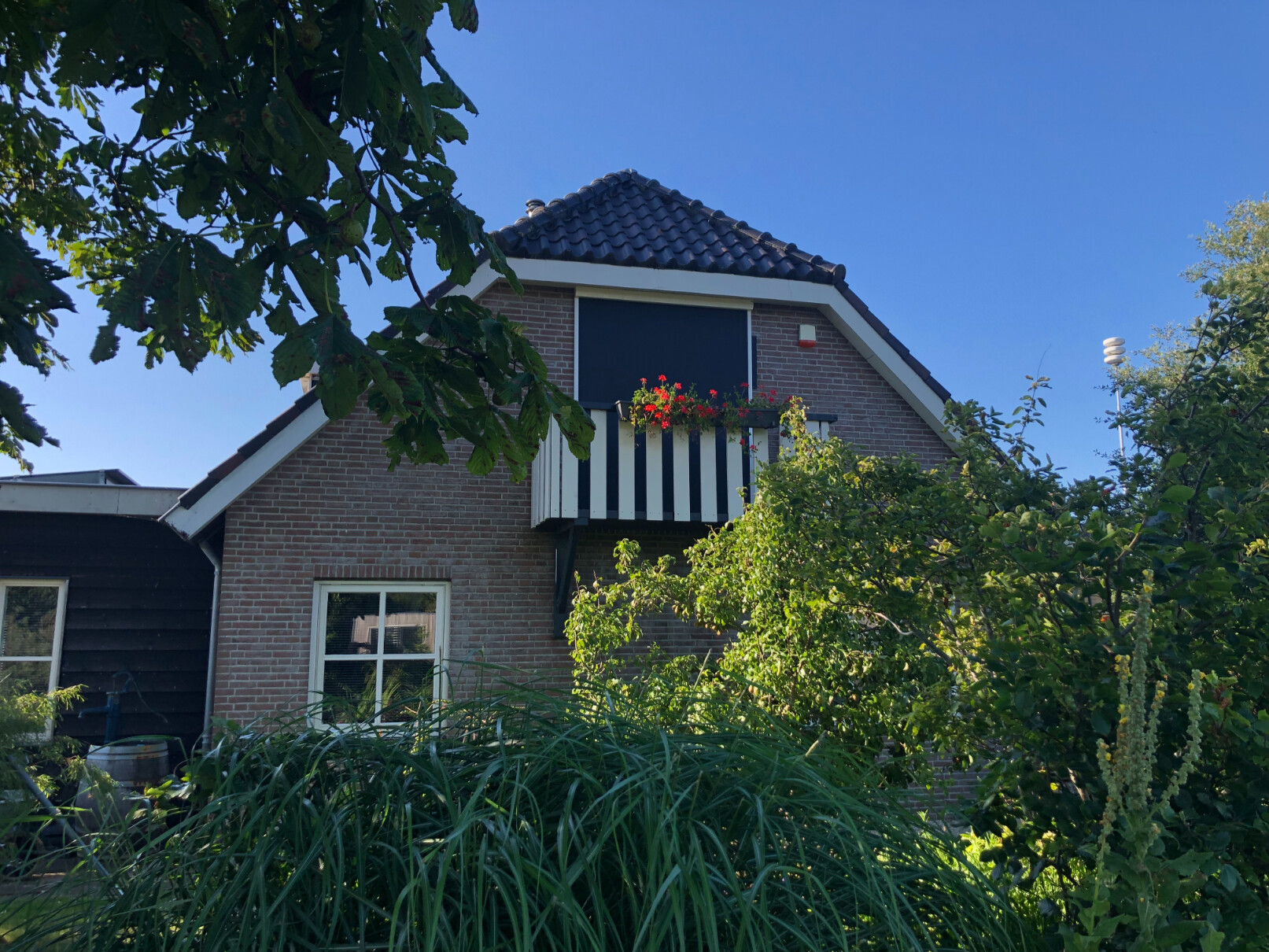 Screen met antracietkleurige doek als verticaal zonnescherm voor balkon van een woonhuis.