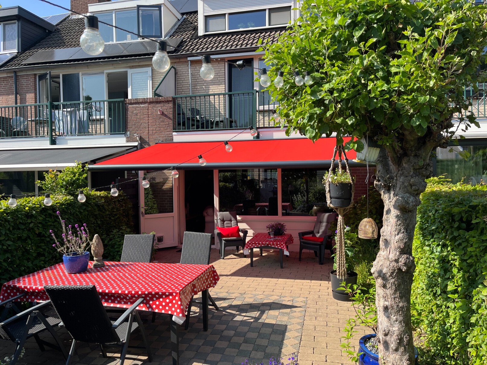 In linkertuin een grijze Rhodos en in rechtertuin een rood Balero knikarmscherm.