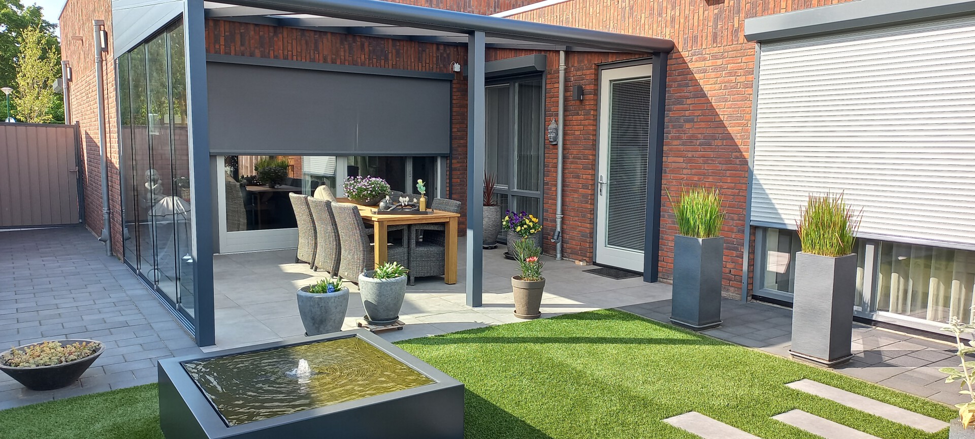 Woonhuis met zowel screen als rolluik met ramen die uitzien op een zonnig terras en gazon.