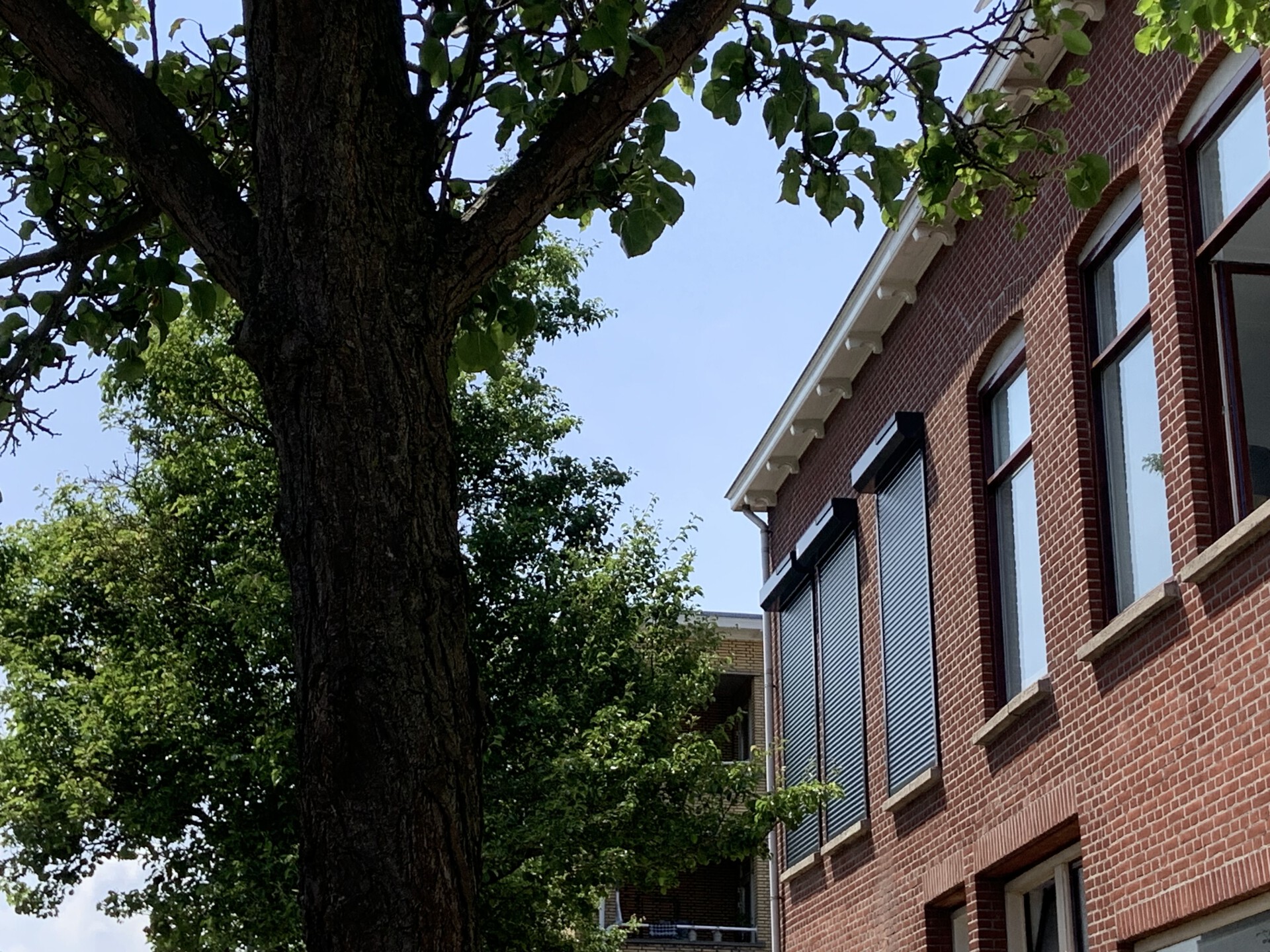 Klassieke woning van rode baksteen met donkere rolluiken van Rainbow Collection.